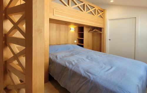 a bedroom with a wooden bunk bed with blue sheets at Le refuge du prieuré - Les Gîtes de la Côte d'Amour in Batz-sur-Mer