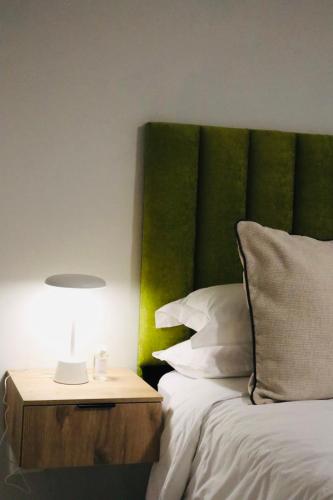 a bed with a green headboard next to a night stand at Atlantis Luxe escape Unit 25 in Uvongo Beach