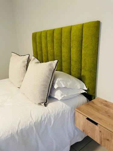 a bed with a green headboard next to a table at Atlantis Luxe escape Unit 25 in Uvongo Beach