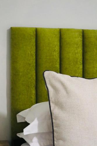a bed with a green headboard with a white pillow at Atlantis Luxe escape Unit 25 in Uvongo Beach