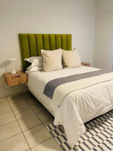 a bedroom with a large bed with a green headboard at Atlantis Luxe escape Unit 25 in Uvongo Beach