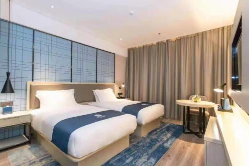 玉林Yishang Hotel Yulin Rongxian Rongzhou Commercial Plaza Branch的有两张床和一台电视的酒店房间