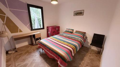 - une chambre avec un lit et une couverture rayée colorée dans l'établissement Maison Parentis en Born, à Parentis-en-Born