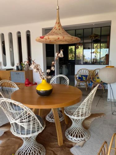 une table avec des chaises et un vase au-dessus dans l'établissement Soleil et serenite au Cap Brun Toulon, à Toulon