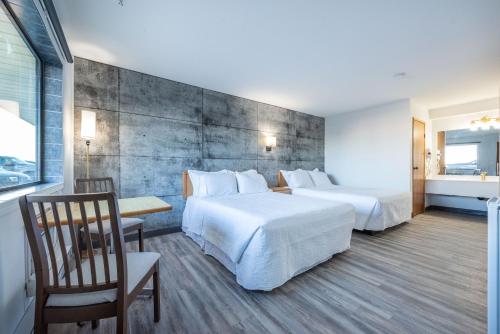 a hotel room with two beds and a table and chairs at Blue Horse Motel in Beiseker