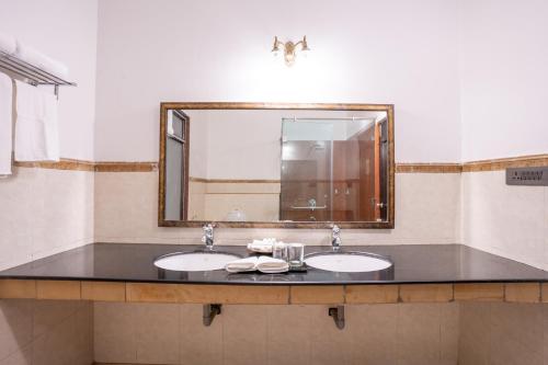 a bathroom with two sinks and a large mirror at JuSTa Alwarbagh Sariska in Alwar