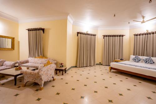 a bedroom with a bed and a couch and a chair at JuSTa Alwarbagh Sariska in Alwar