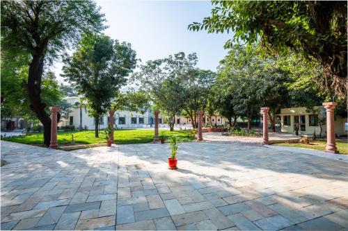 a courtyard with trees and a plant in a red pot at JuSTa Alwarbagh Sariska in Alwar