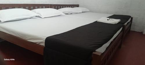 a bed with a black blanket and white pillows at Pure Land Villa in Nallathaniya