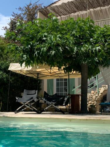 - une table et des chaises sous un parasol à côté de la piscine dans l'établissement Mas du Camisard, à Ribaute-les-Tavernes