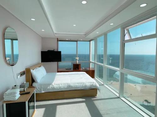 a bedroom with a bed and a view of the ocean at Hotel Haeundae Elysia in Busan