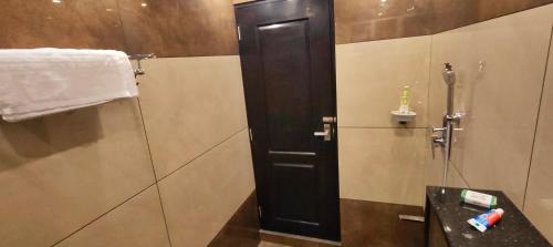 a bathroom with a shower and a black door at Cicadas Nature Resort - A Frame cottages in Wayanad