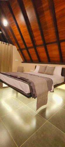 a large bed in a room with a wooden ceiling at Cicadas Nature Resort - A Frame cottages in Wayanad