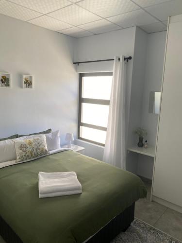 a bedroom with a green bed with a window at Sunbird self-catering B in Windhoek