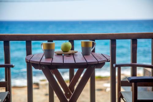 a wooden table with two cups and an apple on it at Porto Sisi Hotel Apartments in Sissi
