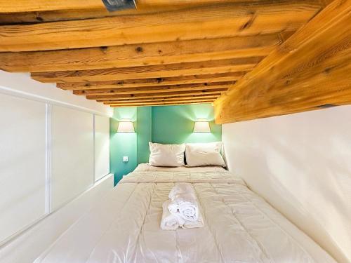 un lit dans une chambre avec un plafond en bois dans l'établissement Le Louis - Lyon 1 - Studio Mezzanine, à Lyon