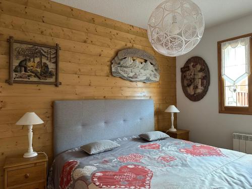 - une chambre avec un lit et un mur en bois dans l'établissement Le Génépi, à Les Deux Alpes
