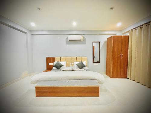a bedroom with a large bed with a wooden headboard at Hotel Grand Aana Inn in Jaipur