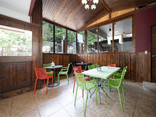 a restaurant with green chairs and tables and windows at Hotel La Casa de la Abuela in Boquete