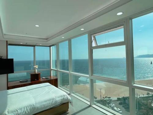 a bedroom with a bed and a view of the ocean at Hotel Haeundae Elysia in Busan
