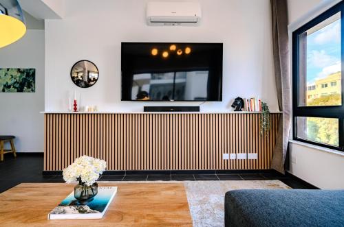 a living room with a television and a vase of flowers on a table at Element Stays City Suite in Nicosia