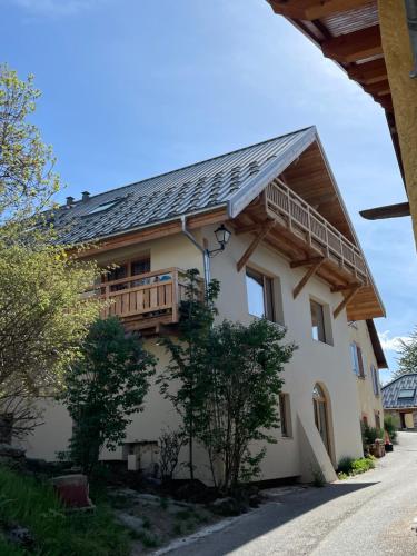 une maison avec un balcon sur le côté dans l'établissement Appartement entre lac & montagne, à Puy-Sanières