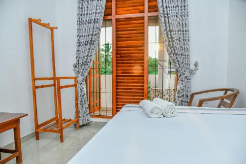 a bedroom with a bed with two chairs and a window at Turtle cove residence in Tangalle
