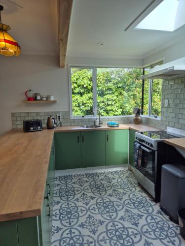 a kitchen with green cabinets and a tile floor at Cosy Getaway 5mins to Doubtful Sound Cruise in Manapouri
