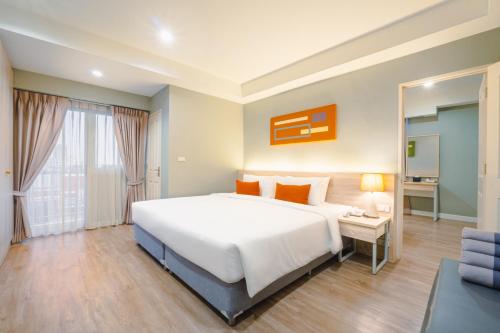曼那Koon Hotel Sukhumvit的卧室里有一张白色的大床和一张书桌