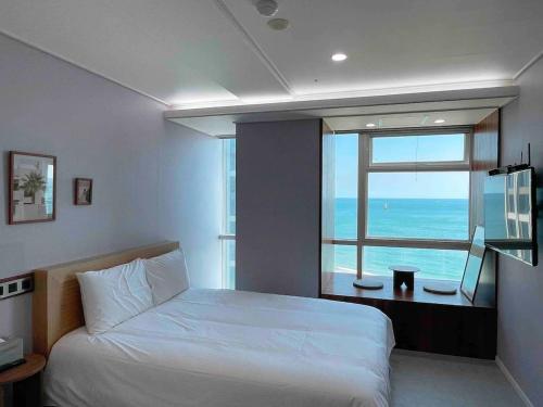 a bedroom with a bed and a large window at Hotel Haeundae Elysia in Busan