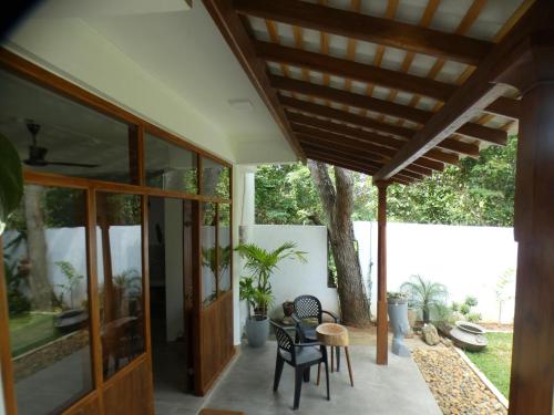 a patio with a table and chairs and a tree at Lisha Mawella in Tangalle