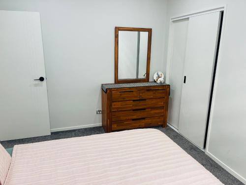 a bedroom with two beds and a dresser with a mirror at Flat bush holiday apartment in Auckland