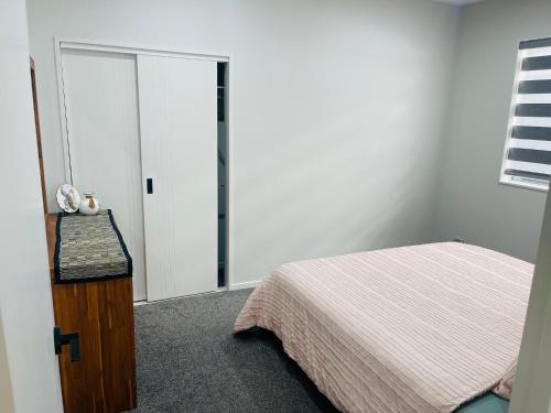 a bedroom with a bed and a sliding glass door at Flat bush holiday apartment in Auckland
