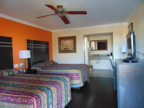 Habitación de hotel con 2 camas y ventilador de techo. en Heart of Texas Motel, en Austin