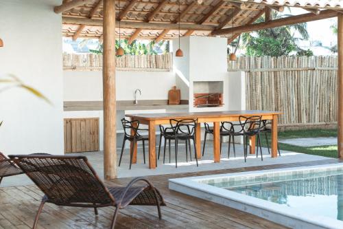 a kitchen with a table and chairs next to a swimming pool at Conforto e Charme, Casa a 360m da Areia in Porto Seguro