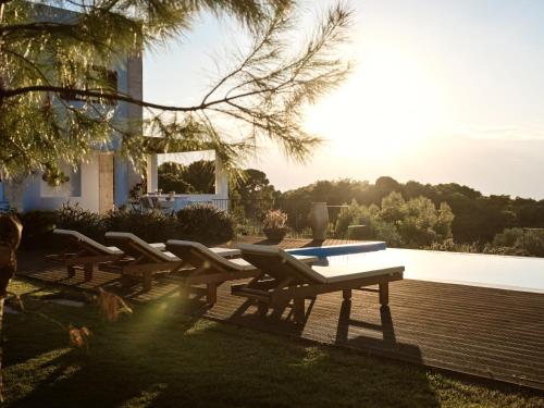 a row of benches sitting next to a pool at Kalas SeaView Residence, a Serene Sanctuary, By ThinkVilla in Zakynthos Town