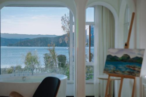 a room with a tub and a view of the water at Lakeside Retreat - LuguLake Lijiang in Zuosuo