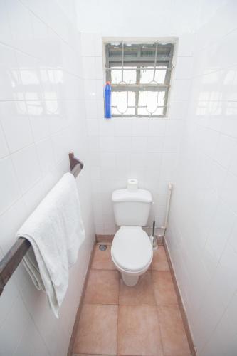 a white bathroom with a toilet and a window at Zing gardens E06 in Mombasa