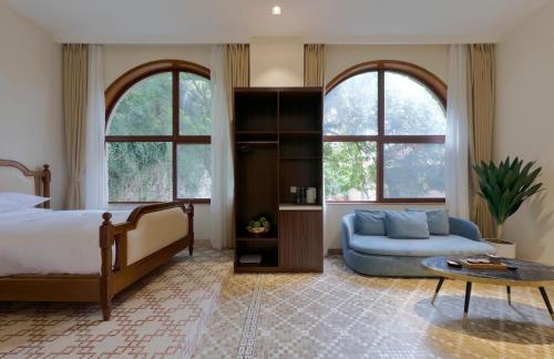 a bedroom with a bed and a couch and two windows at Linggan Linghai Hotel in Xiamen