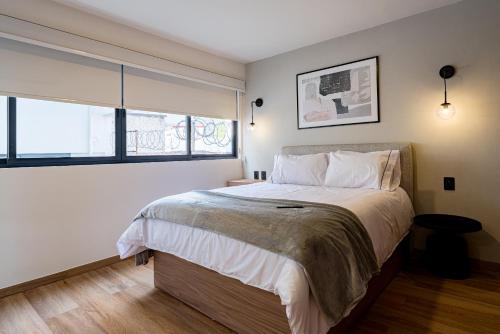 a bedroom with a large bed and two windows at Mint Roma Residence in Mexico City