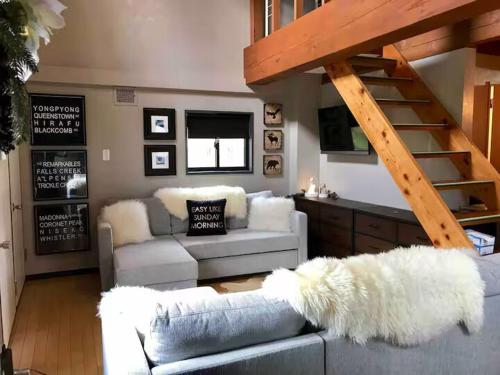 a living room with a couch and a staircase at Casa Bell Cabin Niseko in Niseko