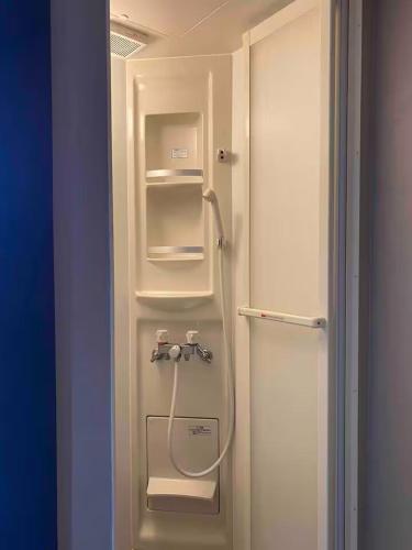 a white refrigerator with a shower in a room at Casa Bell Cabin Niseko in Niseko