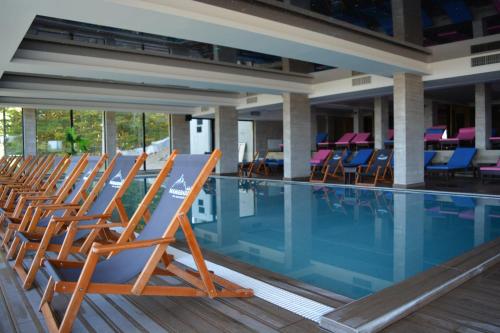 Una fila de sillas junto a una piscina. en Okili apartman S11 Milmari resort Kopaonik, en Kopaonik