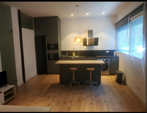 a kitchen with a island and two bar stools at Apartamento nuevo y tranquilo con acceso independiente in Madrid