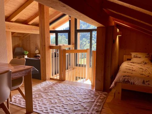 une chambre avec un lit, un bureau et une fenêtre dans l'établissement Charmant appartement sous combles, neuf, aux Gets