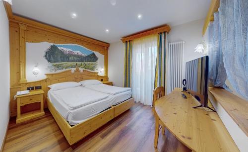 a bedroom with a bed and a desk and a television at Hotel Madonna delle Nevi in Folgarida