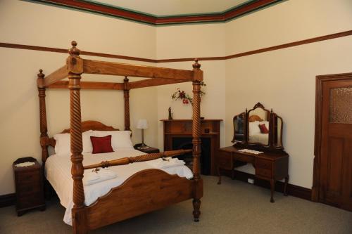 a bedroom with a wooden canopy bed and a mirror at Cockburn House in Jamestown