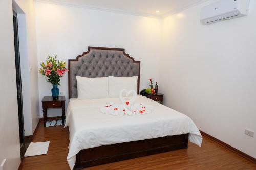 a bedroom with a bed with white sheets and flowers at Royal Hotel Trâu Quỳ in Thạch Cầu