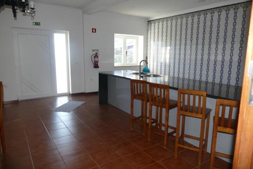 a kitchen with a counter and two chairs and a table at Casa nos Penedos in Arcos de Valdevez