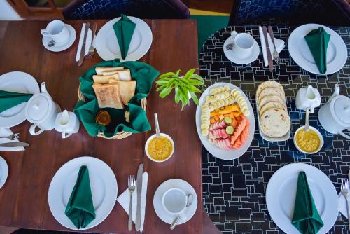 a wooden table topped with white plates and bowls of food at The Residence Ella in Ella